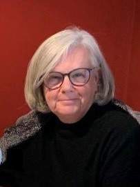 portrait photo of Jane Hessami. Jane has grey hair cut in a short bob style and is wearing a black polo neck jumper.  She is also wearing glasses.